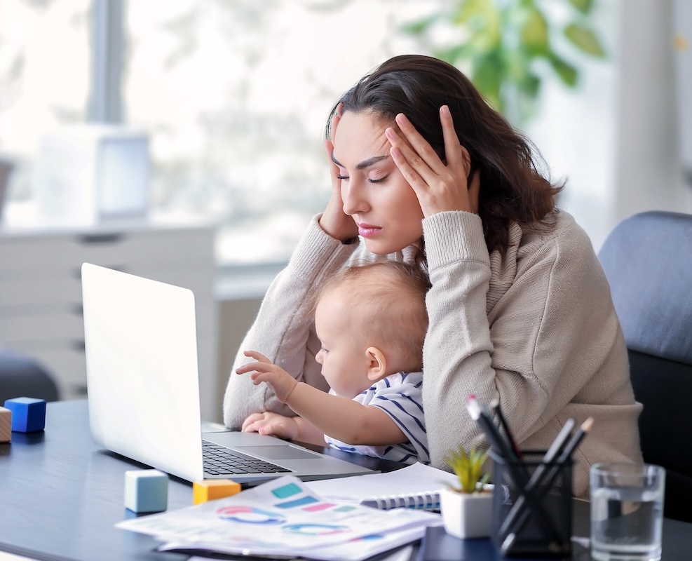 Stressed mother with her baby working in office
